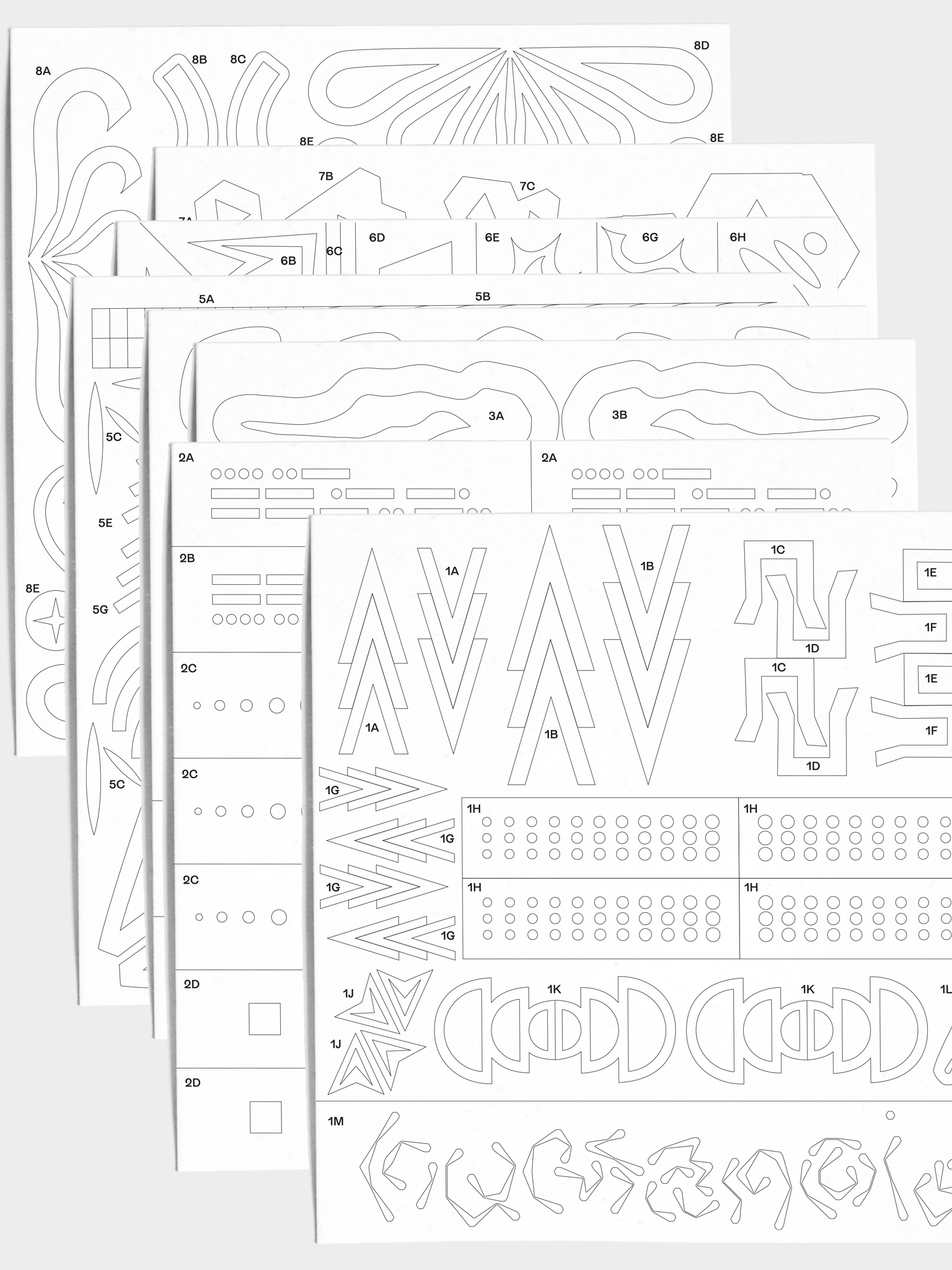 Closeup of 8 stencil sheets stacked on top of each other with various geometric shapes, dots, stars, and stripes.